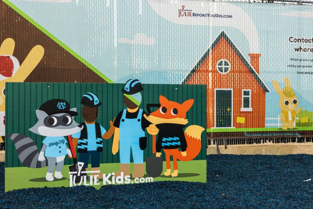 fence wrapping at a playground with a sign in the foreground that reads "juliekids.com"