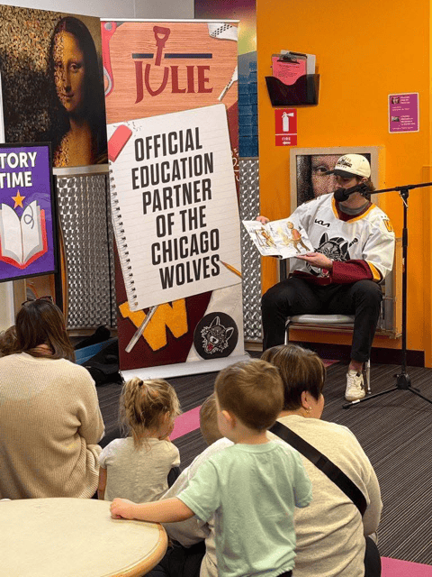 A Chicago Wolves reads from a storybook to a classroom of students